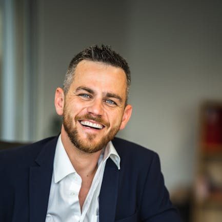 Home Business professional in suit smiling confidently in a modern office environment.